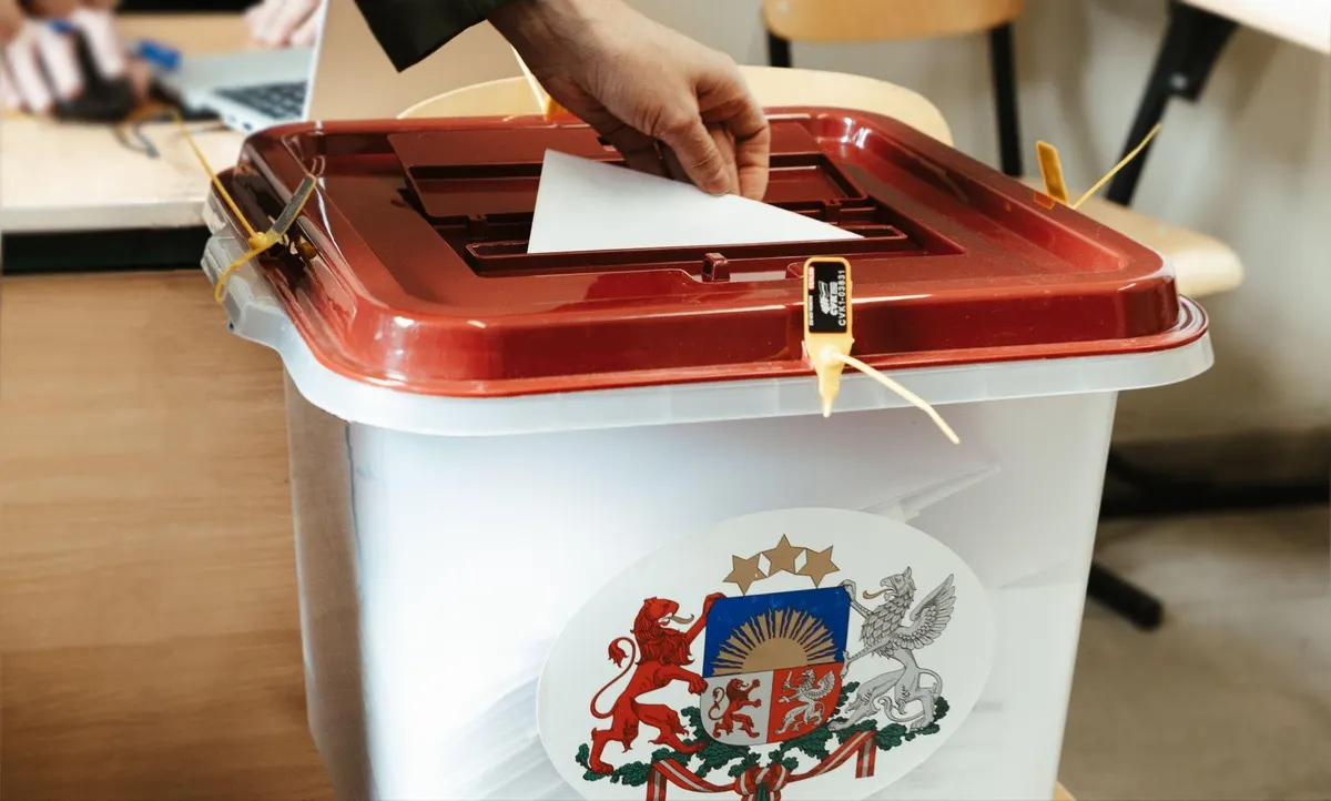 Roka ieliek aploksni aizplombētā vēlēšanu kastē ar Latvijas ģerboni